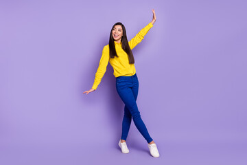 Fototapeta na wymiar Full length photo of charming attractive young woman dance raise hands look empty space isolated on violet color background