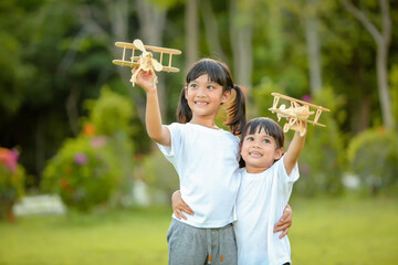 Two cute little girl asia playing toy airplane on nature in the