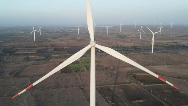 Aerial view over the farm landscape and wind turbines generating clean renewable energy. Renewable energy production for the green ecological world.
