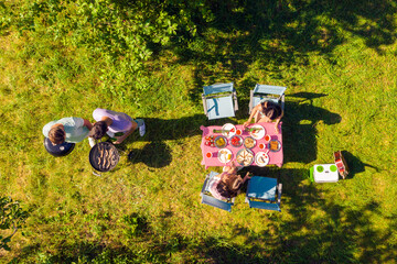 High above angle view men cooking barbeque outdoors girls drinking beer having conversation enjoying summer sunny day
