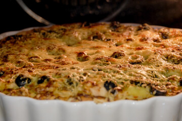 Pizza with pineapple, olives and chicken covered with cheese is cooked in the oven