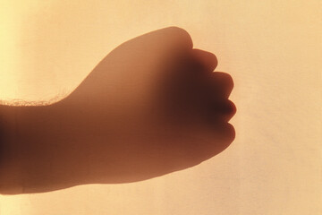 Shadow of a man hand shows a fist gesture, silhouette