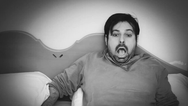 Black-and-white macro shot: a sleeping man's reaction to something scary or annoying happening in his bedroom.
