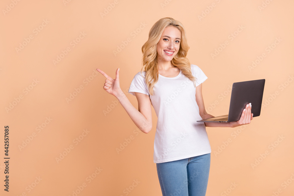 Poster Portrait photo blonde woman showing copyspace keeping laptop isolated pastel beige color background