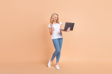 Full length body size photo blonde woman gesturing like winner keeping laptop isolated pastel beige color background