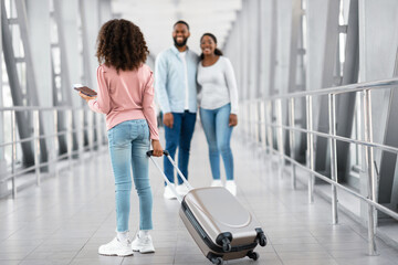 Happy black parents meeting kid in airport
