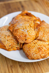 Raw chicken thighs with condiments on a white porcelain plate close up top view shallow depth of...