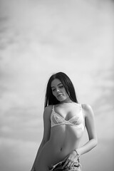 Close up portrait of a young beautiful brunette woman in white bra posing on a background of blue...