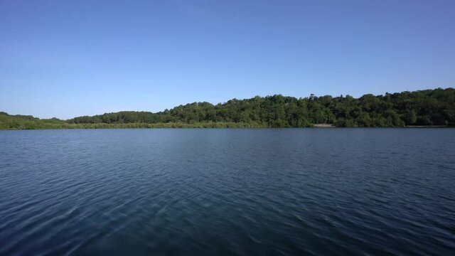 Lake Mouriscot western France on clear day with depth sticks showing, Slow pan right reveal shot
