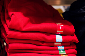 Stack of red t-shirts on a shelf in a supermarket close up, selective soft focus