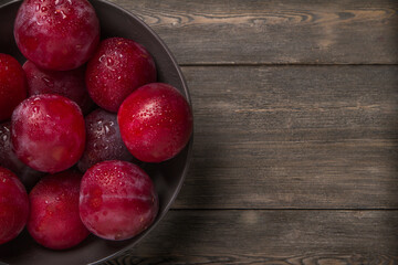 Plum on a dark and light wooden background.