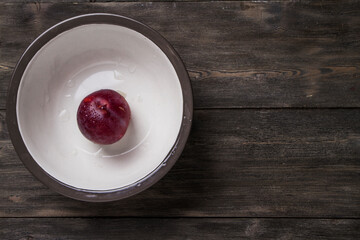 Plum on a dark and light wooden background.