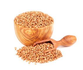 Roasted buckwheat grains in olive bowl and scoop, isolated on white background. Dry brown buckwheat groats.