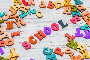 School creative flatley. On a wooden white table lie multicolored letters with the inscription school.