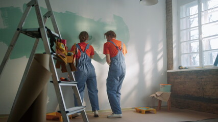 Fototapeta na wymiar Happy couple painting wall indoors. Family dancing during decoration in home.