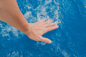 Fototapeta na wymiar Hand touching the cool sea in summer