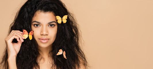Fototapeta premium african american woman with orange butterflies on hair isolated on beige, banner