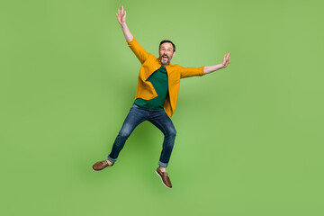 Fototapeta na wymiar Full body photo of positive mature happy man jump up air raise hands enjoy isolated on green color background