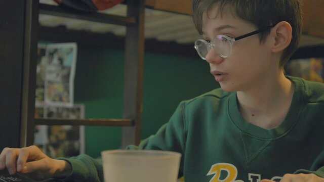 An attractive young boy works diligently on his homework at his desk in his bedroom.
