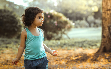 Portrait little adorable cute Caucasian curly hair girl smiling, doing activity, playing, running in outdoor garden during evening with happiness, amusement with copy space. Education Concept.