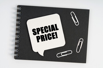 On the notebook are white paper clips and a sign with the inscription - SPECIAL PRICE