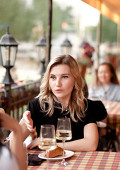 Women at cafe drinking white wine and talking. Communication and friendship concept.