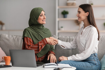 Mature Muslim Businesswoman Shaking Hands With Young Female In Office