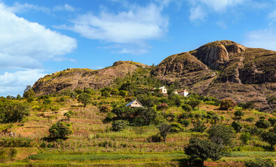 Typical Madagascar landscape - green and yellow rice terrace fields on small hills with clay houses in region near Ambositra