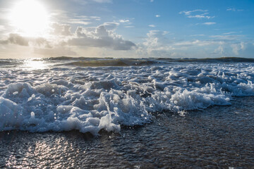 Rushing waves at beach with blue cloudy sky