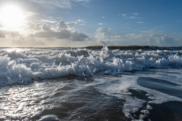 Rushing waves at beach with blue cloudy sky