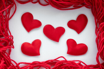 Frame around the edges of the frame made of red thread with hearts in the middle for knitting handmade and hobby on a white background from fabric February 14 Valentine's Day