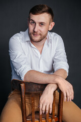 A man sits on a chair hanging his hands