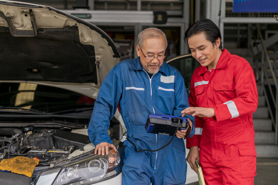 Elderly vehicle mechanic use an obd2 car diagnostics device scanner to interpreting automotive error codes. Senior professional mechanic maintenance the engine in garage workshop. Auto repair service