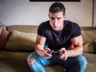 Attractive guy playing videogames with joystick in hand