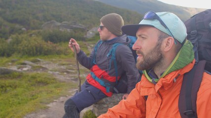 Lost in the mountains. Tourist instructor and assistant sit on a stone. They are tired of awaiting...