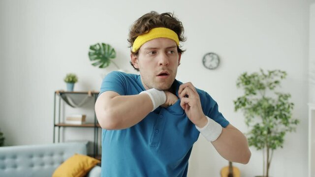 Portrait of funny sportsman in retro clothing showing ok hand gesture and winking looking at camera indoors at home. People and emotions concept.