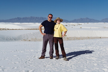 happy dad posing with his daughter in a sunny day in the white sands dunes over the background of sand dunes and mountains in White Sands National Park, New Mexico, USA
