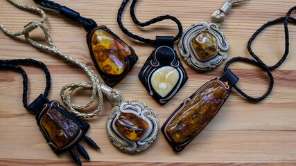 Variety of leather pendants with different  Baltic amber stones on a wooden background. Ancient...