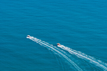 Naklejka premium Top view of two boats sailing at high speed. Aerial view of boats in motion on blue water.