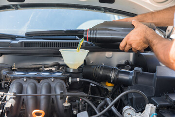 Car servicing mechanic pouring oil