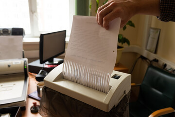 a man destroys paper documents in a shredder