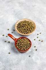 Green peppercorns in a small bowl and spoon.
