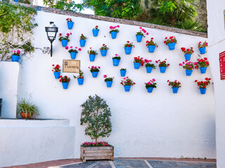 Beautiful old town in Marbella on a sunny summer day. White walls decorated with blue flower pot.