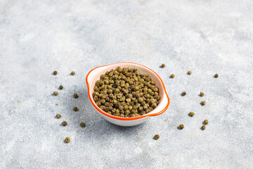 Green peppercorns in a small bowl and spoon.