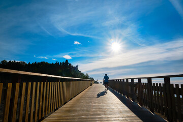 Obraz premium Beautiful sunrise from wooden boardwalk with silhouette of a man walking
