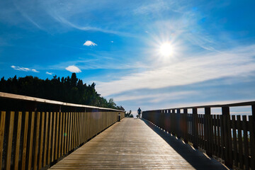 Fototapeta na wymiar Beautiful sunrise from wooden boardwalk with silhouette of a man walking
