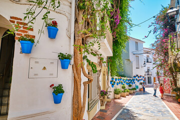 Beautiful old town in Marbella on a sunny summer day. White walls decorated with blue flower pot.
