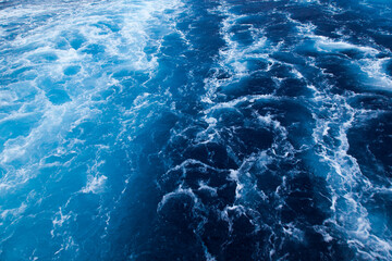 Ocean close up. Background of blue water with white foam.
