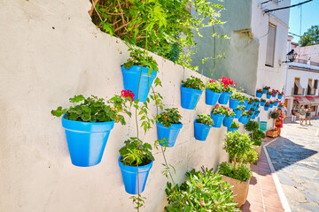 Beautiful old town in Marbella on a sunny summer day. White walls decorated with blue flower pot.