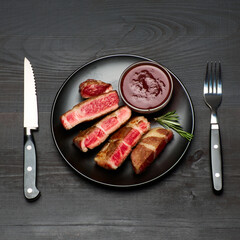 Grilled roated beef steaks on black ceramic plate